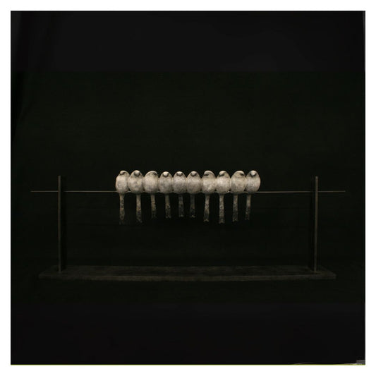 Row of metallic objects on a reflective surface against a black background