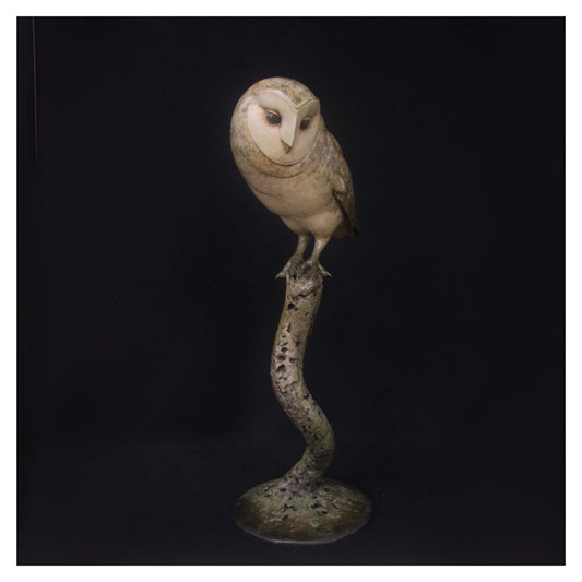 Statue of an owl perched on a branch against a black background