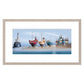 Framed artwork of colorful boats and a lighthouse on a beach.